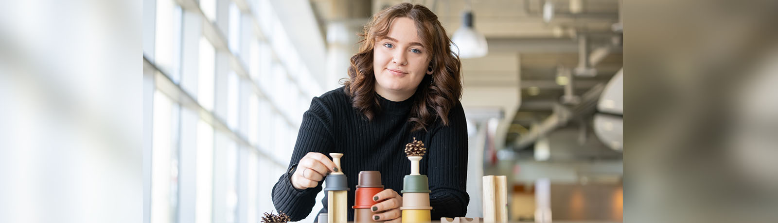 Courtney Smith stacks colourful cups, wooden spools and pinecones