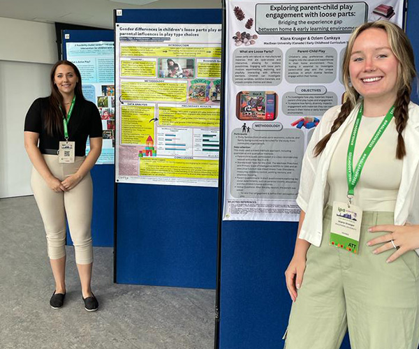 Two students stand in front of their poster displays at a conference