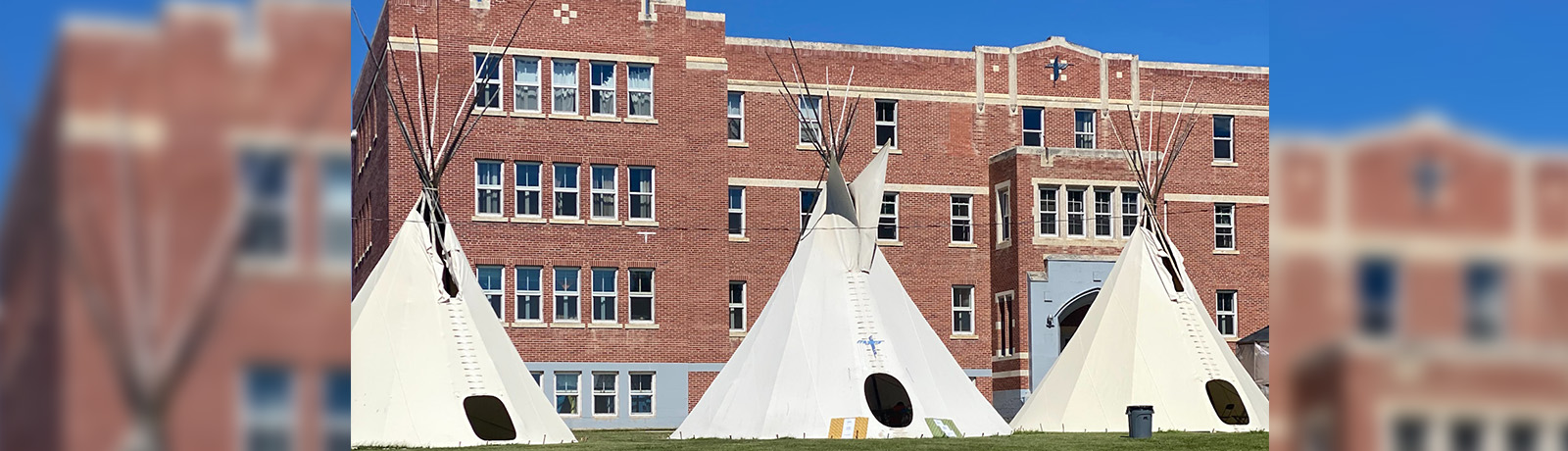 Ceremonial tipis sit in front of the former residential school, Blue Quills.