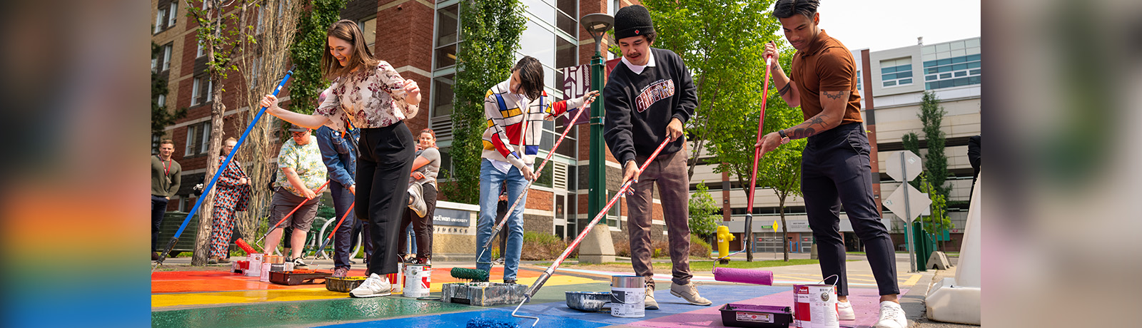 Volunteers give MacEwan's Pride sidewalks a fresh pop of colour in May 2023.