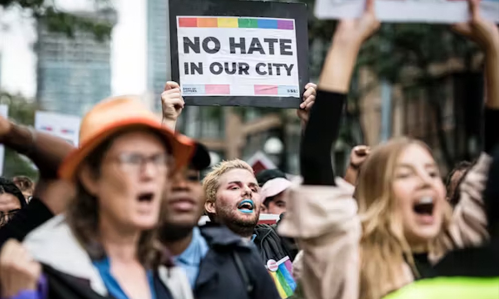 A person holds up a sign at a Toronto rally that says "no hate in our city"