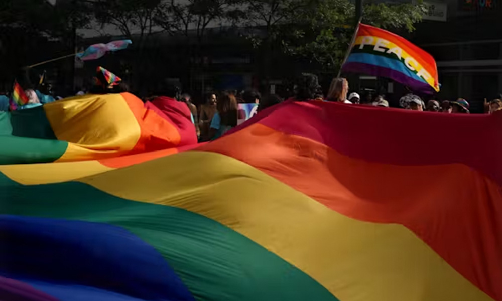 A rainbow parachute and flags blow in the wind at the Toronto Pride Parade