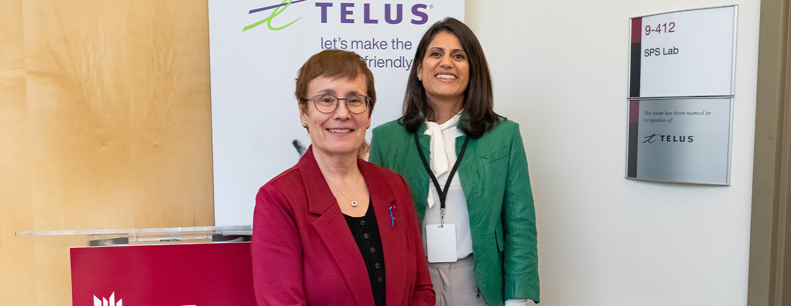 Dr. Annette Trimbee and Zainul Mawji stand in front of a lab in the Robbins Health Learning Centre that is marked with a sign that bears the TELUS logo.