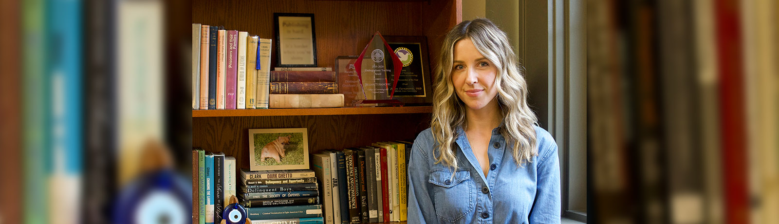 Dr. Turanovic stands in front of a bookshelf