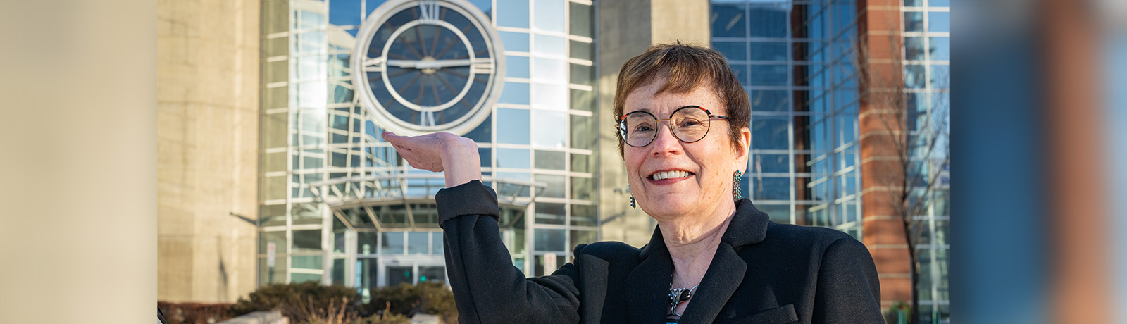 Dr. Trimbee stands outside Building 6 in front of the Douglass Clock