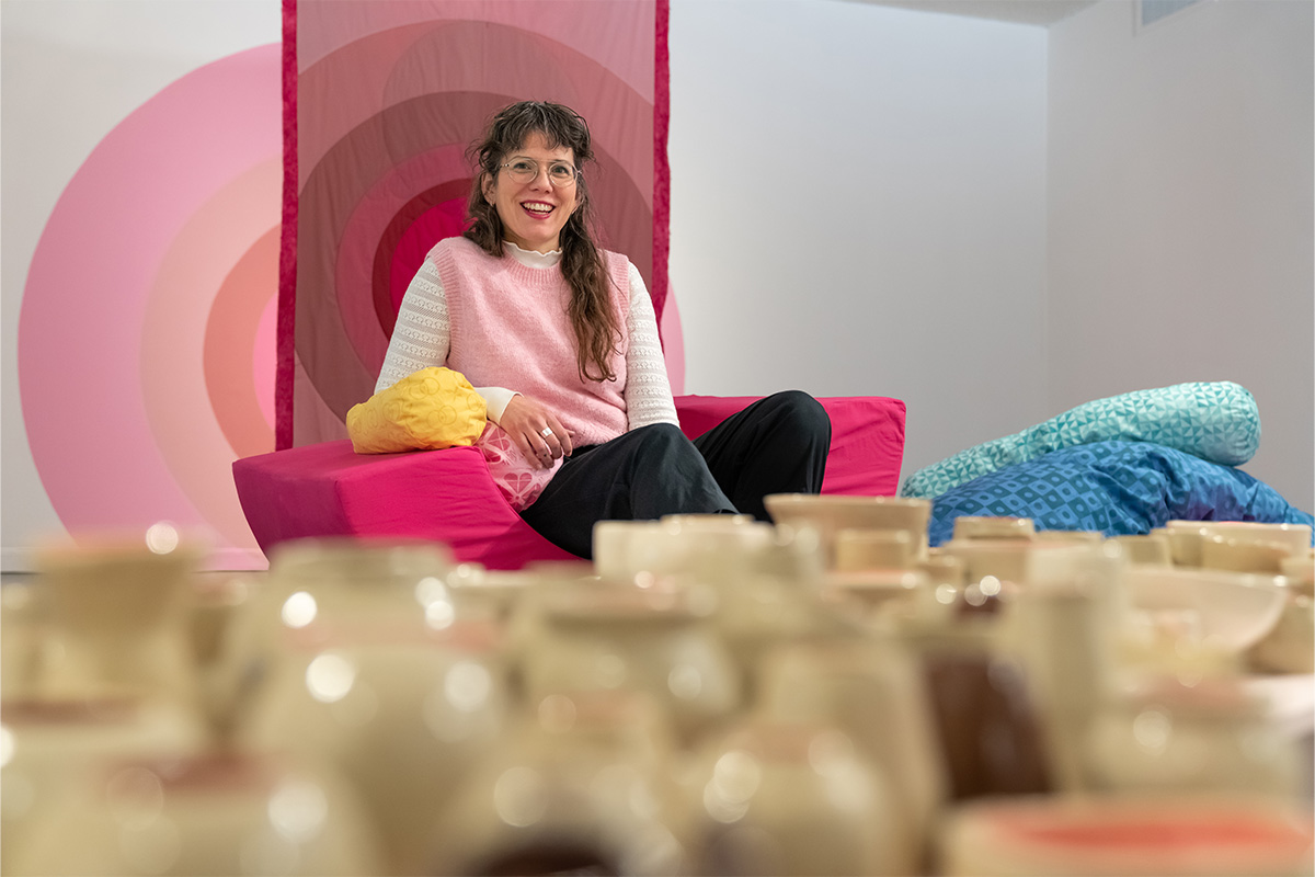 Kristy Reeves sits on some of the cushions in her art installation, next to some of her pottery.