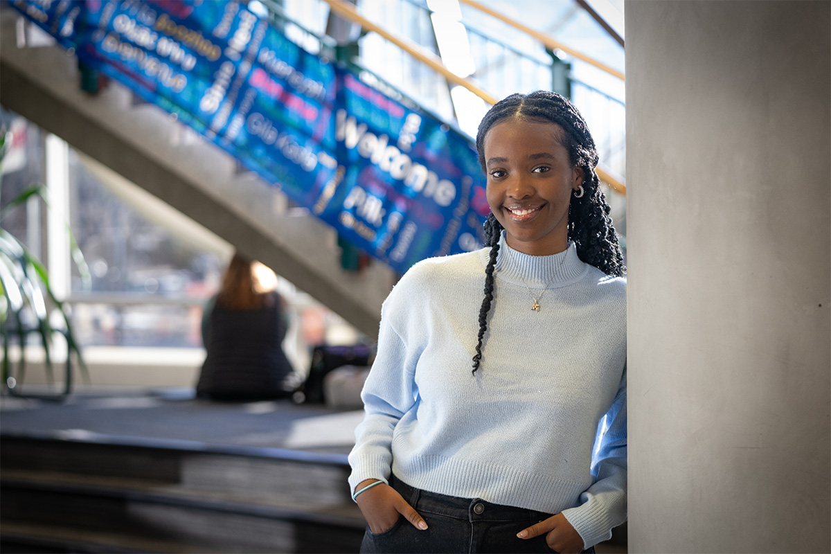 Emilie Rubayita leans against a pillar in the library