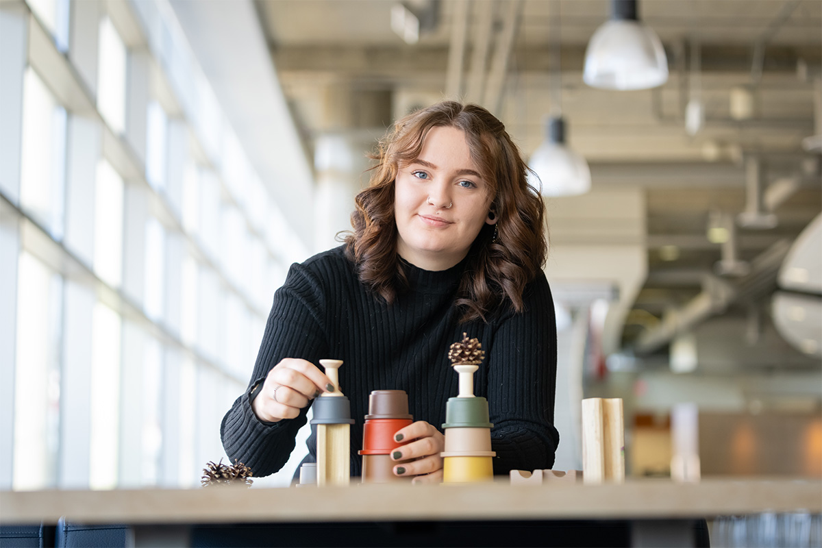 Courtney Smith plays with measuring cups and acorns in the SAMU Building on campus.