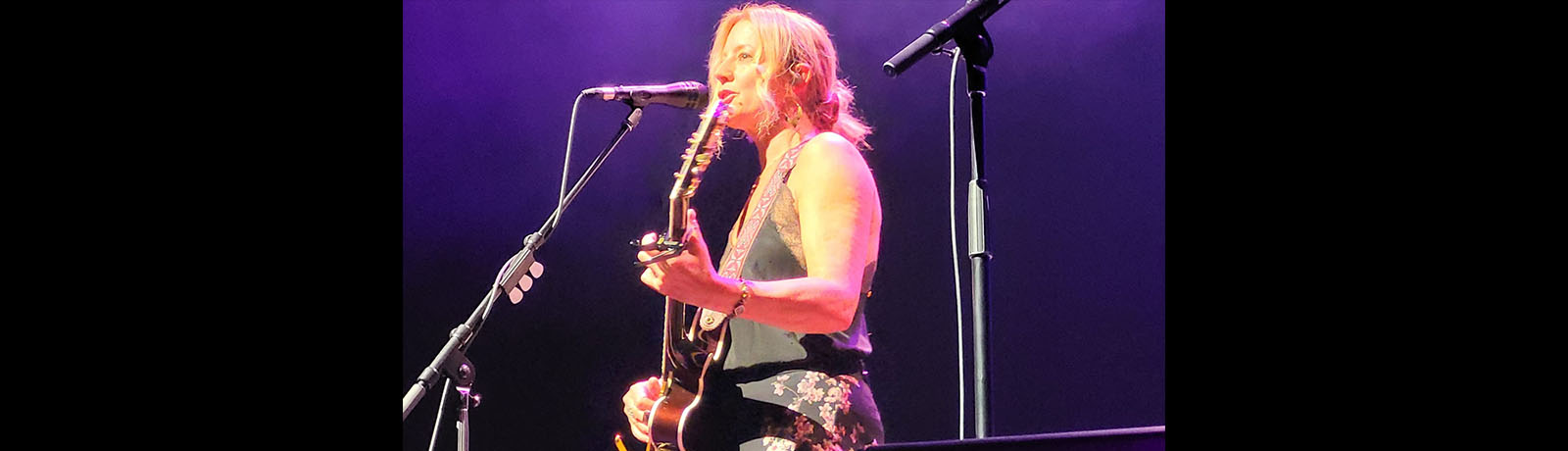 Sarah McLachlan holding a guitar and singing on stage