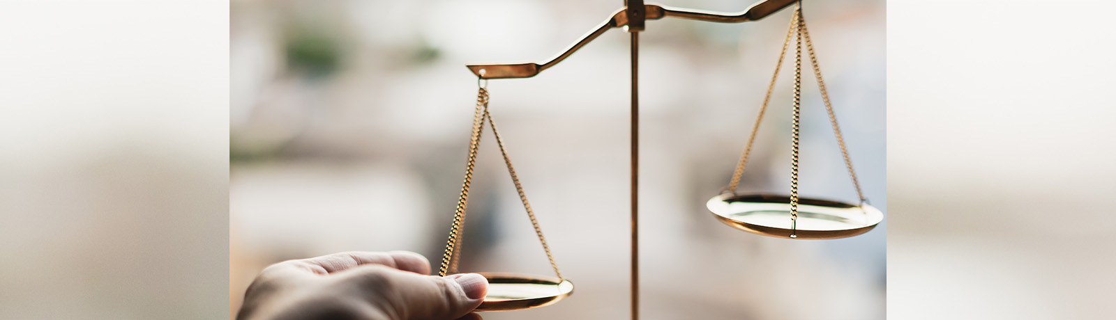 A hand holds down one side of brass scales.