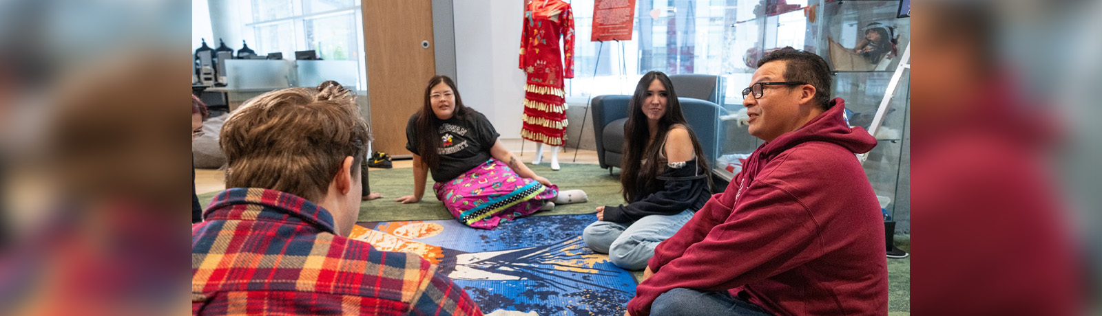 A group of people sit in a circle, talking in MacEwan's kihêw waciston Indigenous Centre.
