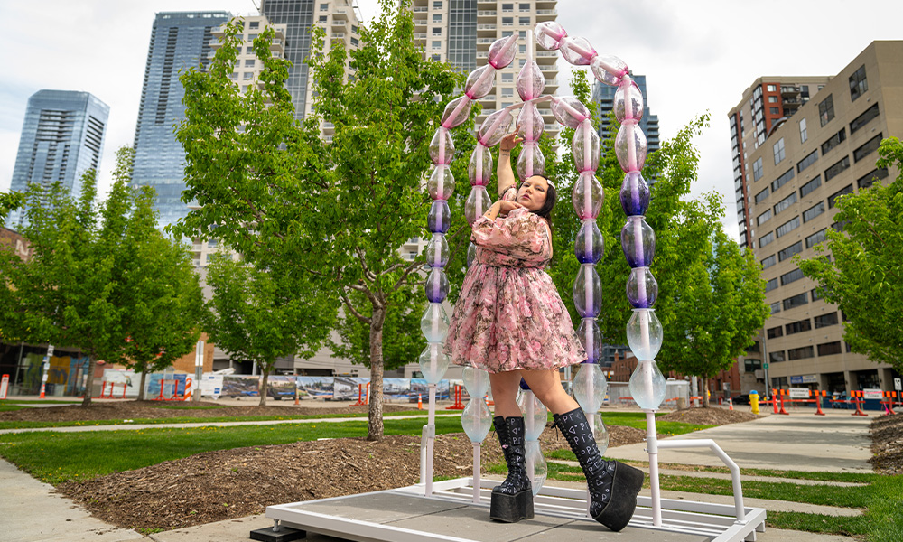 Cheyenne Rain LeGrande poses in front of her installation of huge colourful glass beads in downtown Edmonton