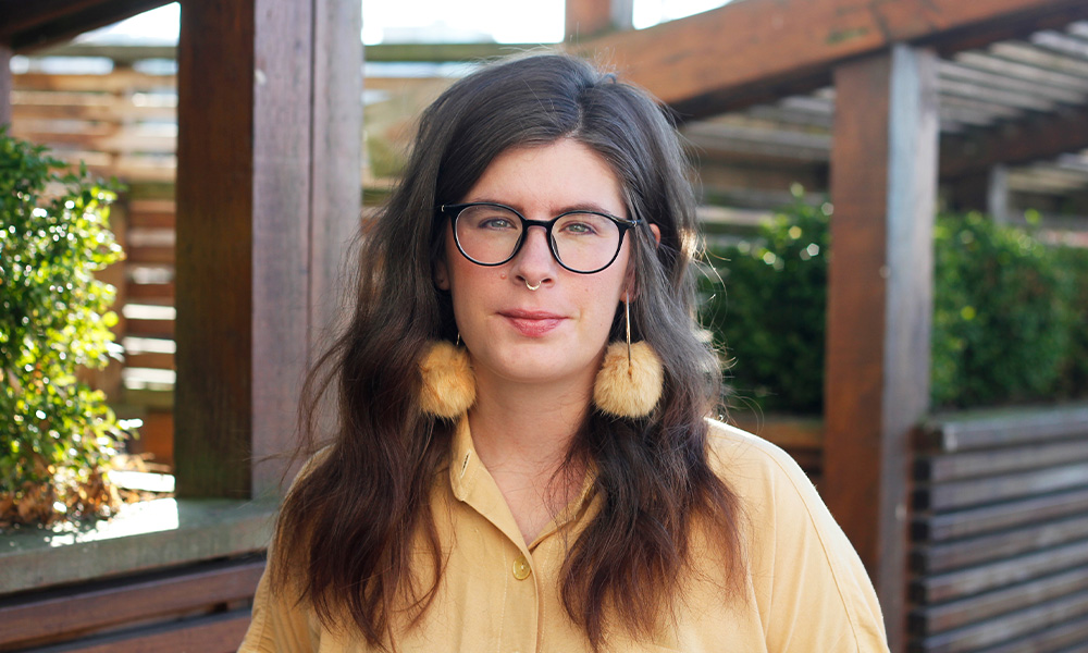 Jessica Johns wears yellow fluffy earrings and a yellow shirt.