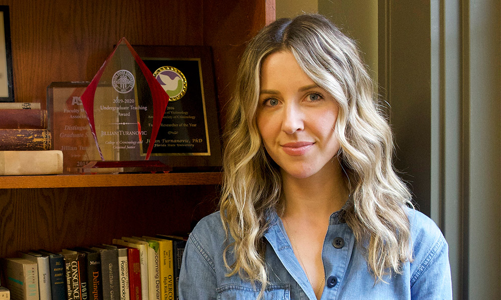 Dr. Jillian Turanovic sits in front of a bookcase.