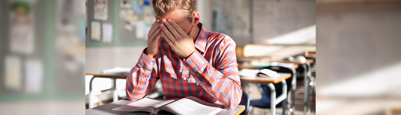 A student covers his face with his hands in frustration