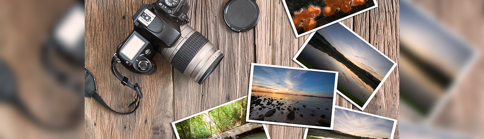 A camera and a series of summer landscape photos sit on a wooden table.