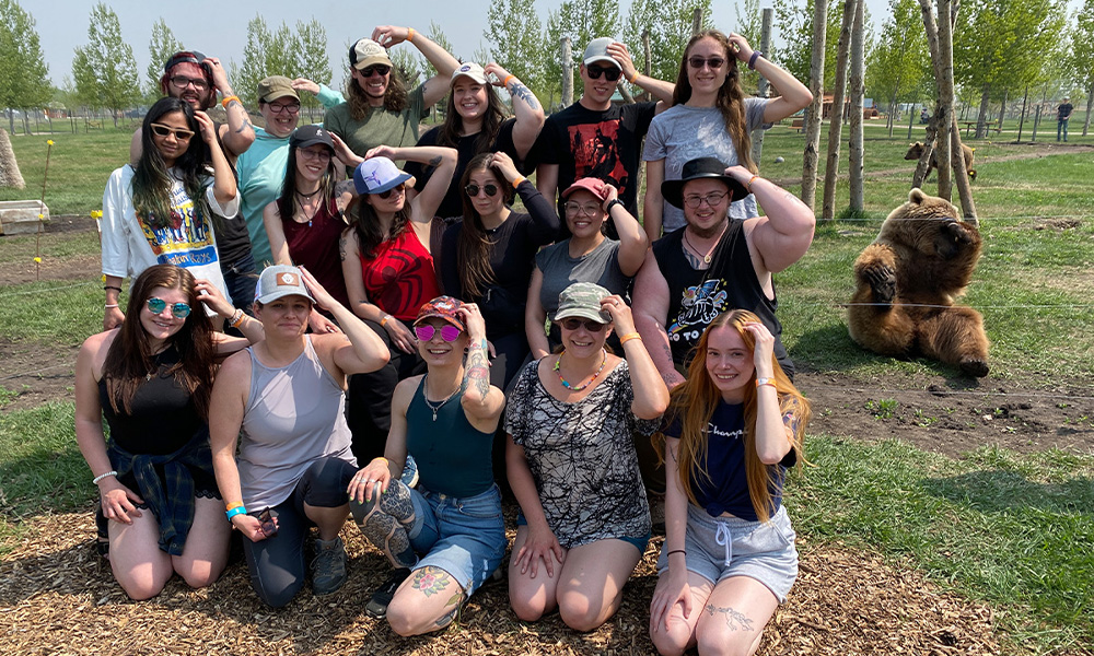 Students pat their heads while a bear in the background pats his head.