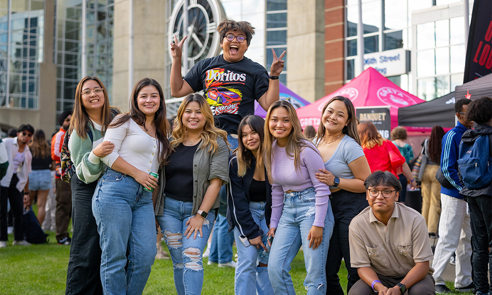 Students pose together on the lawn in front of the clock tower during Fall Fest.