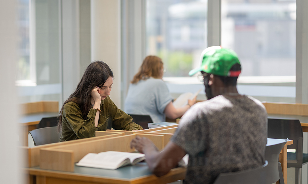 Three students sit at desks individual desks studying