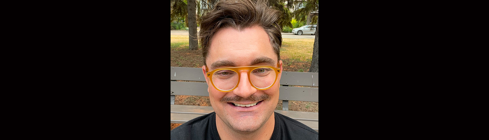 A self-taken photo of a man with brown hair and orange glasses.