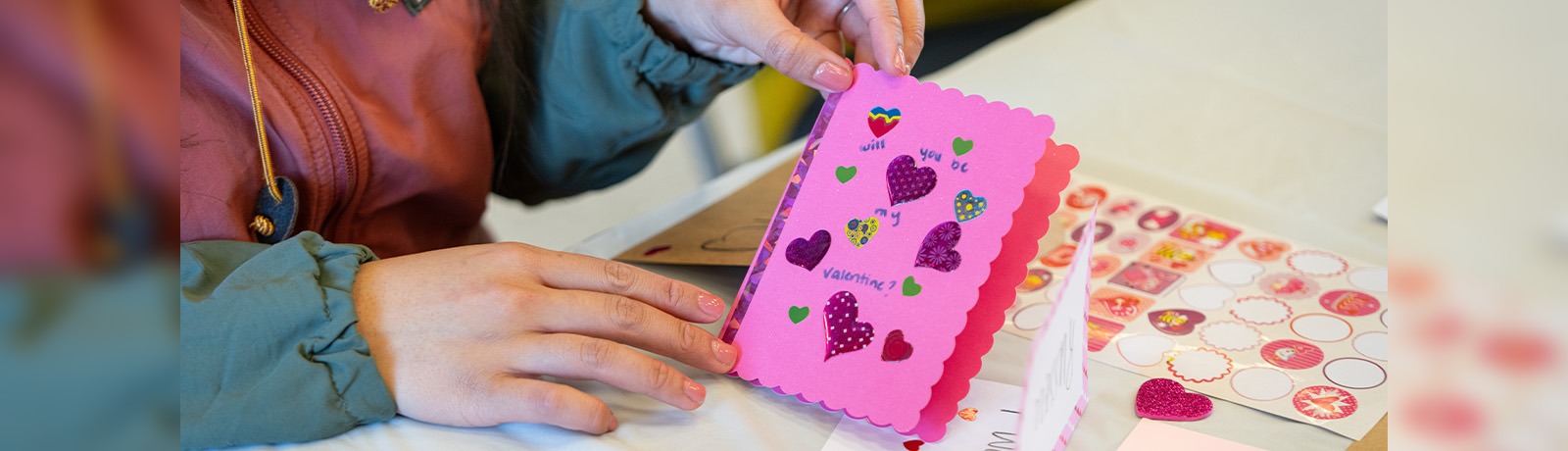A pink Valentine's card is decorated with colourful heart-shaped stickers.