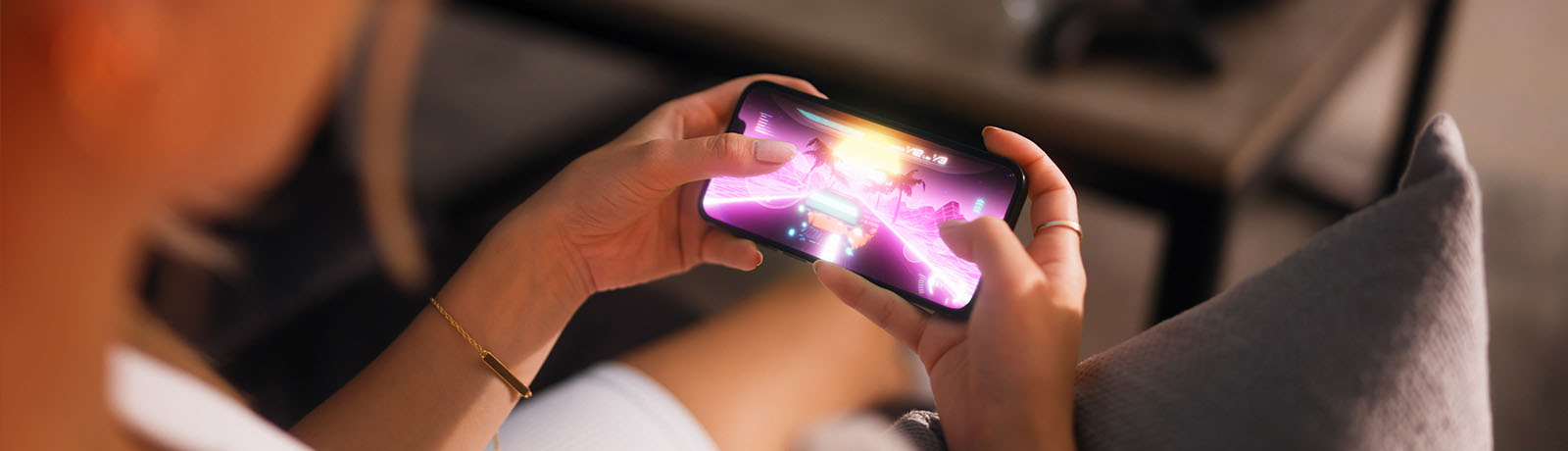 A woman holds a phone horizontally in her hands while playing an online game