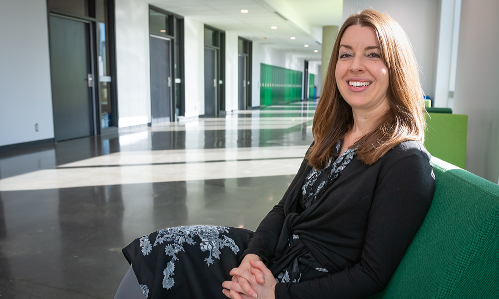 Dr. Sarah Copland sits on a green chair in Allard Hall