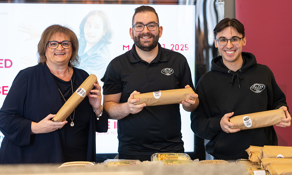 Three people stand together holding sandwiches