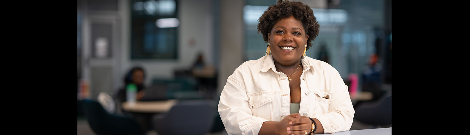 Chadene stands at a table in the library