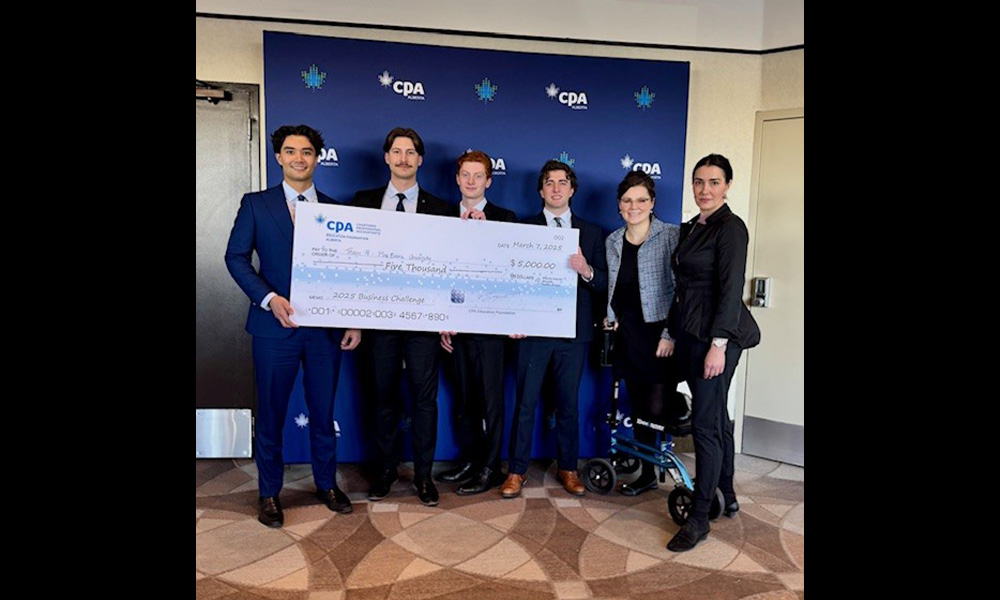 Four students hold a giant cheque with their faculty supervisors to the side.