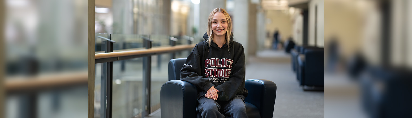 A student sits in a black chair, smiling.