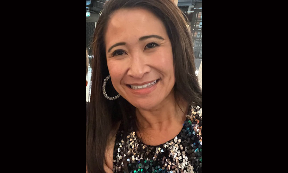 a woman in a sequin shirt smiling at the camera