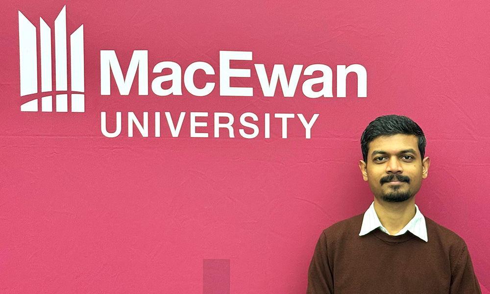 a man stands in front of a sign saying MacEwan University