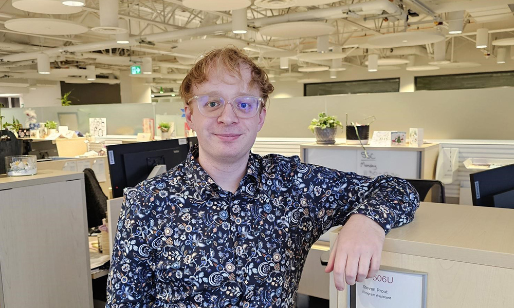 a man standing against the wall of a cubicle
