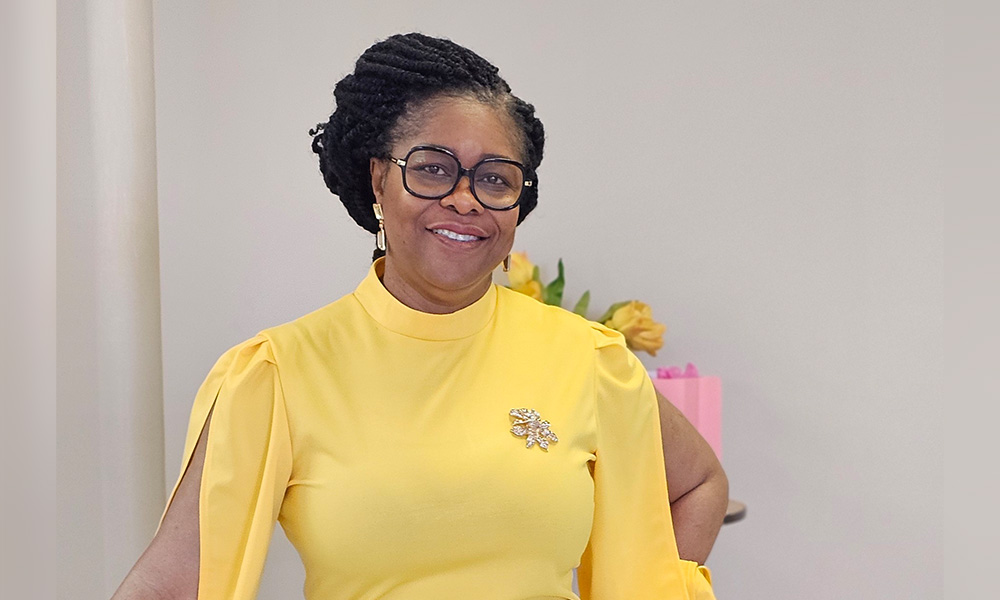 a woman in a yellow dress stands smiling at the camera