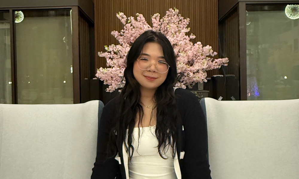 Jaysel Arroyo sits on a white sofa with pink flowers behind her