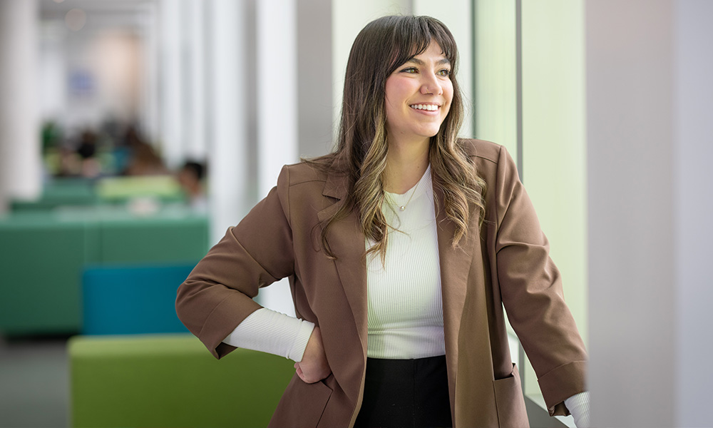 Sarah Barthel stands beside a series of windows in Allard Hall
