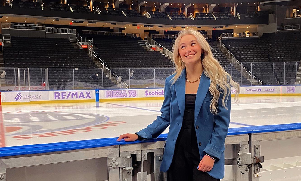 Brooke Mayer stands by the boards beside the ice at Rogers Place