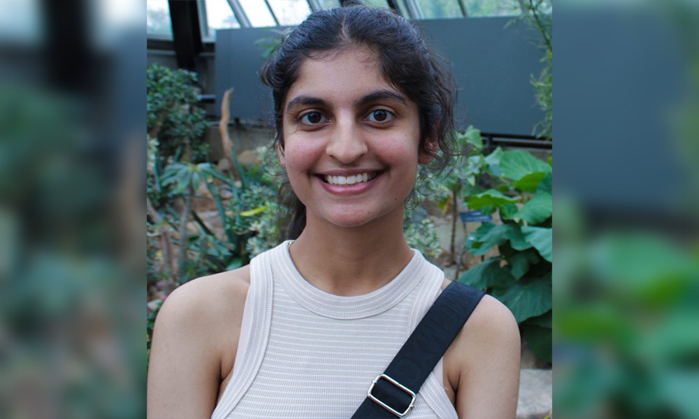 a woman smiling standing in front of an indoor garden