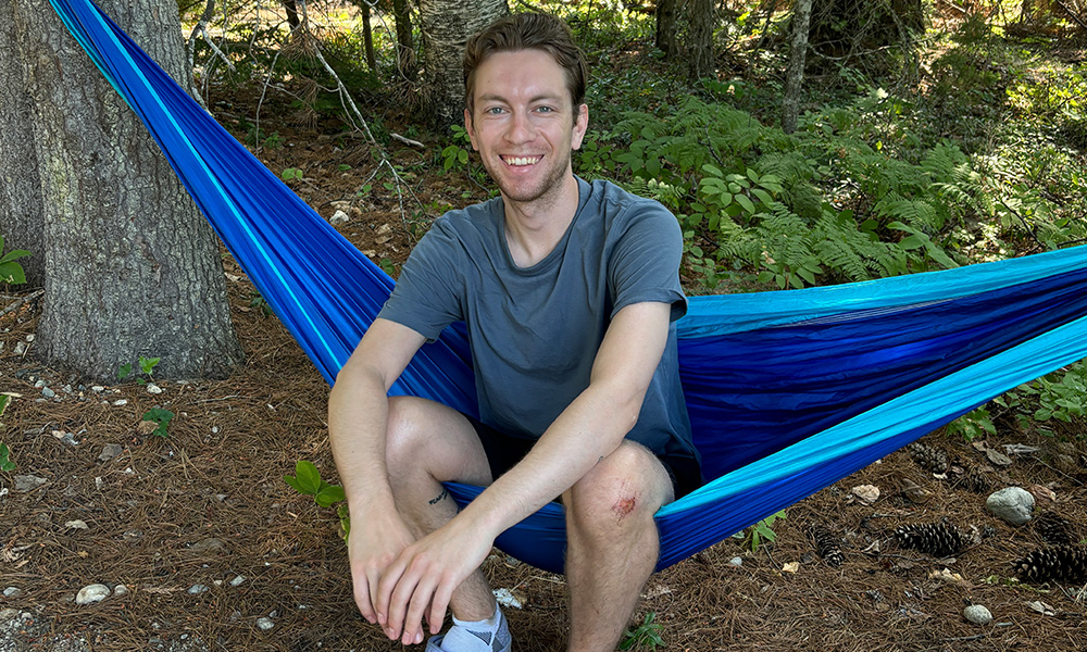 a man sitting in a hammock smiling at the camera