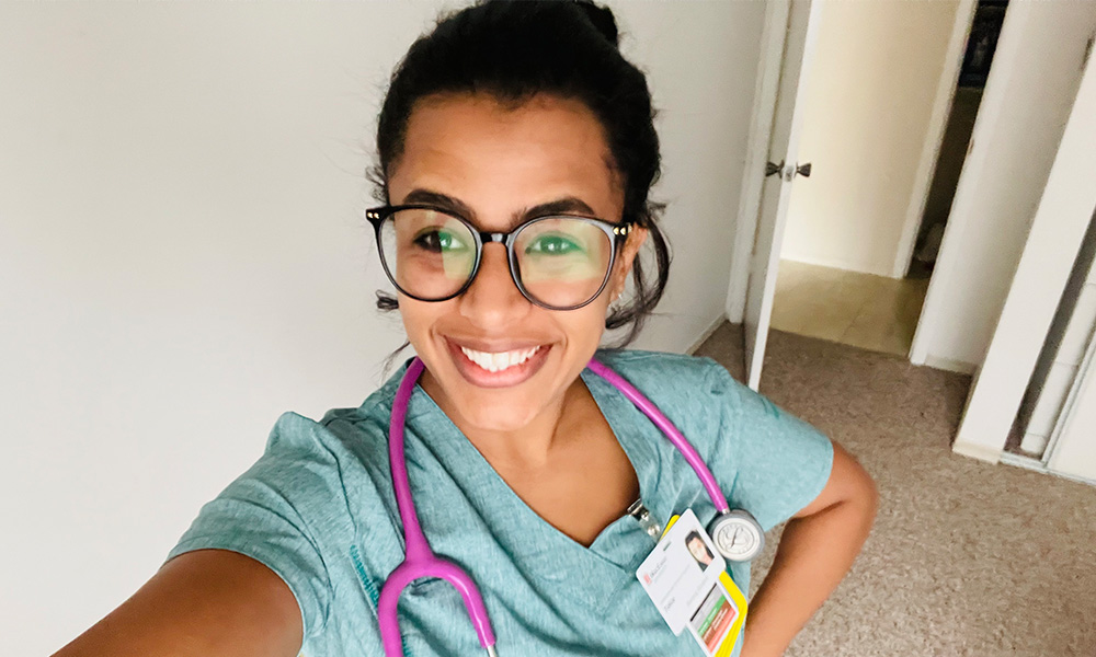 a woman in scrubs smiling at a camera taking a selfie