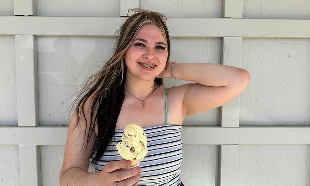 Abigale Chase holds an ice cream cone and smiles, wearing a black-and-white striped tank top.