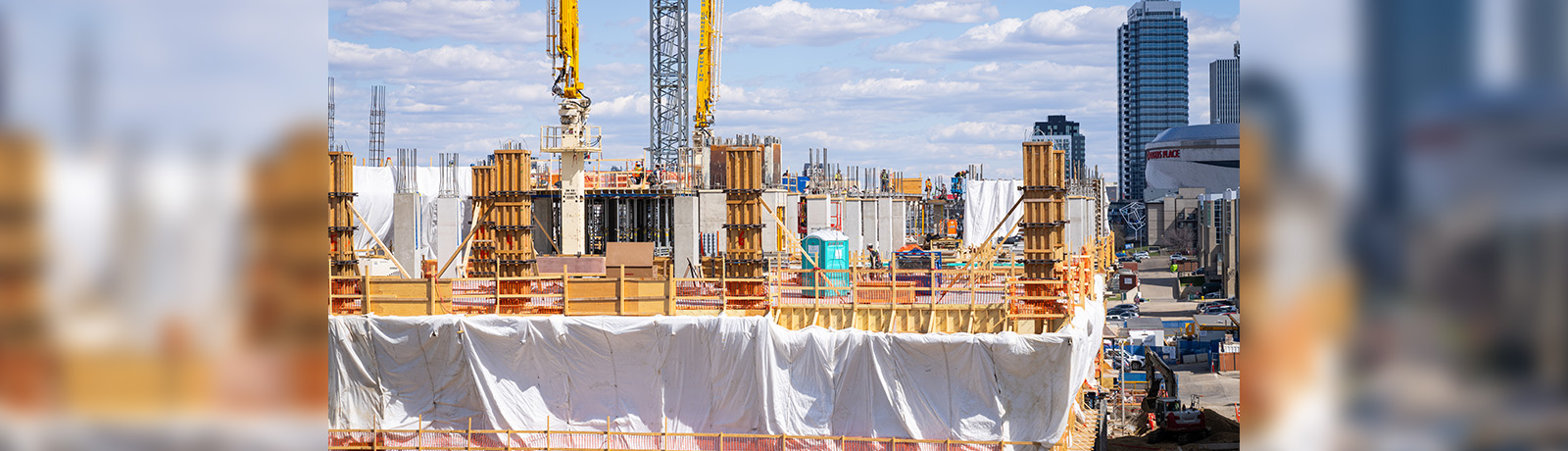 The School of Business Building construction site, partially covered in white sheeting, with downtown Edmonton in the background.