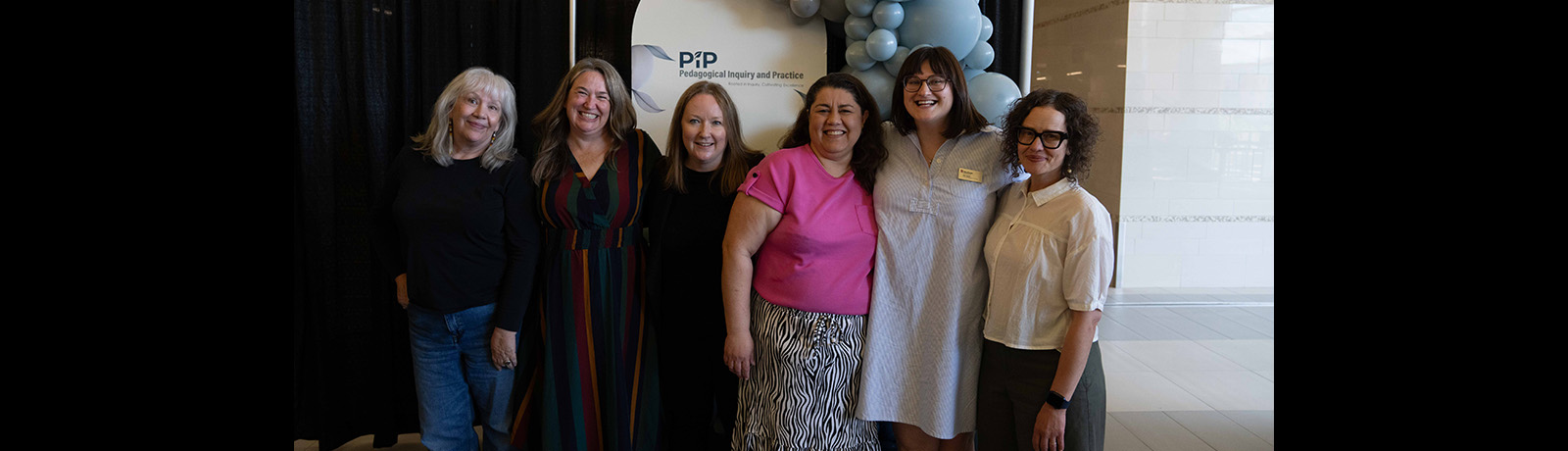Six women stand in front of balloon and a sign for Pedagogical Inquiry and Practice