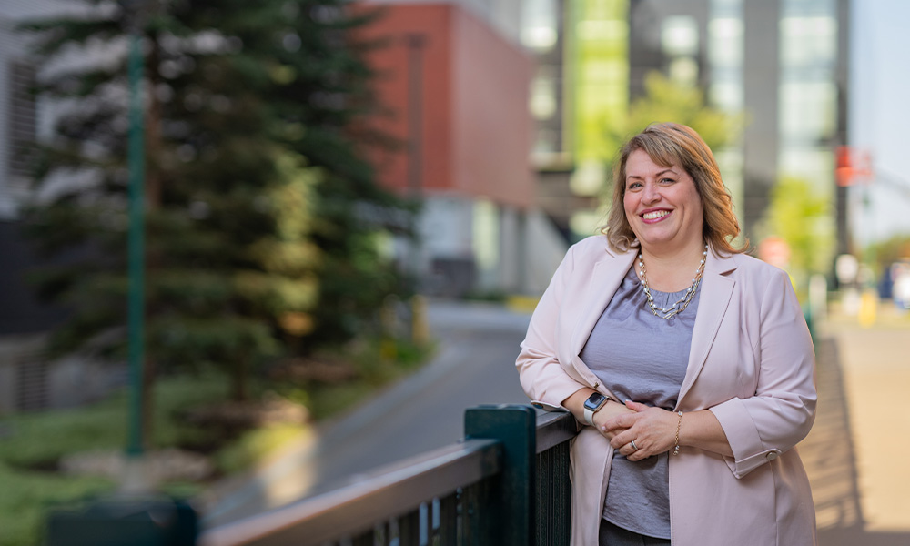 Michelle French wears a grey cardigan and leans on a railing outside of the West Parkade.