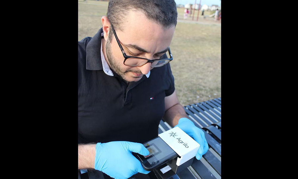 A researcher wears gloves while holding the Agrilo tool