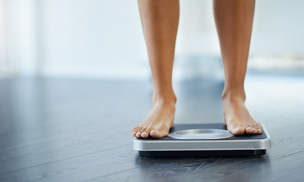 Bare feet standing on a bathroom scale.