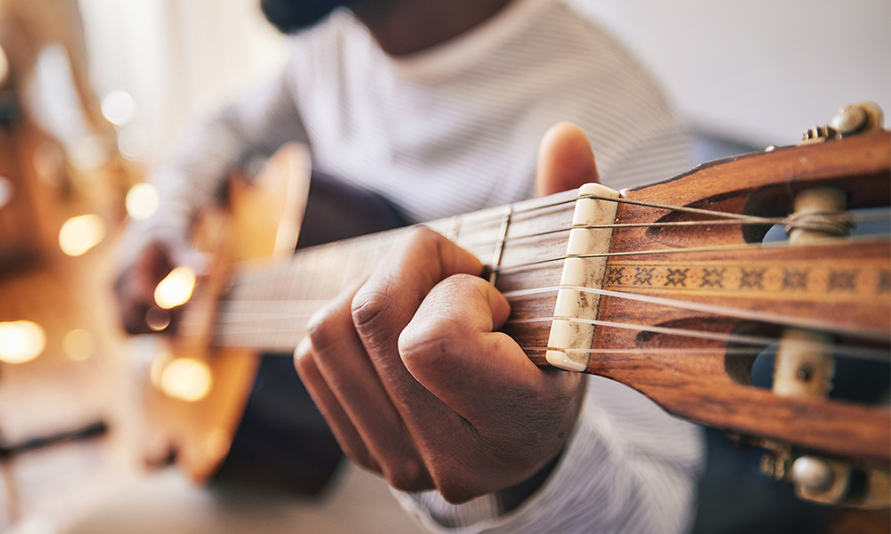A closeup of a hand on the neck of a guitar