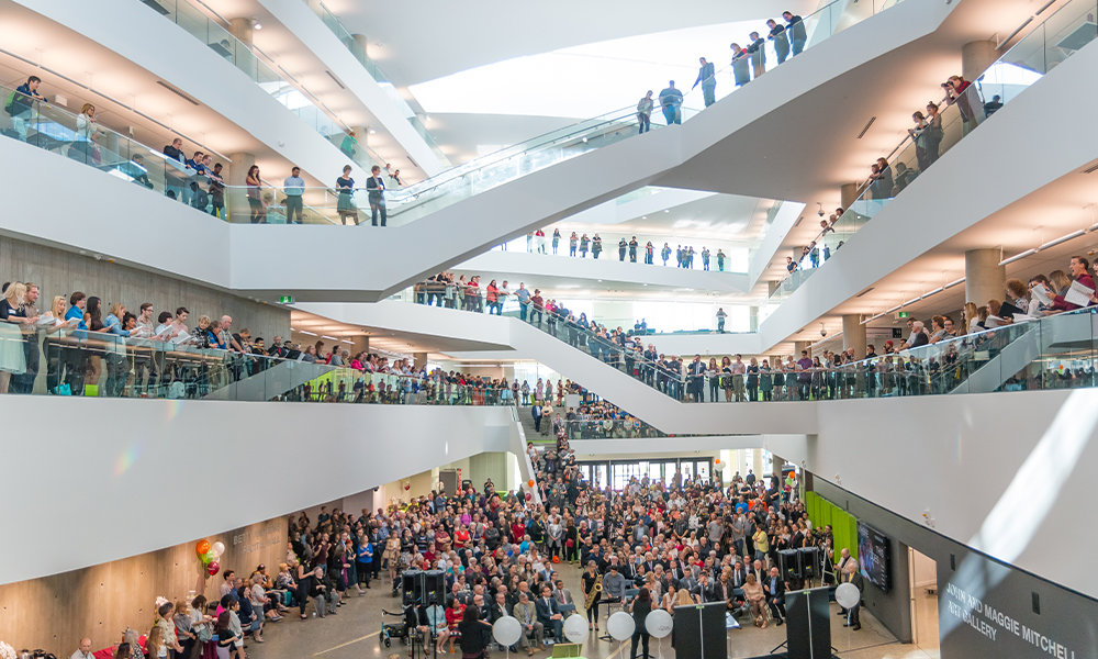 a building with various angled staircases, full of people milling about