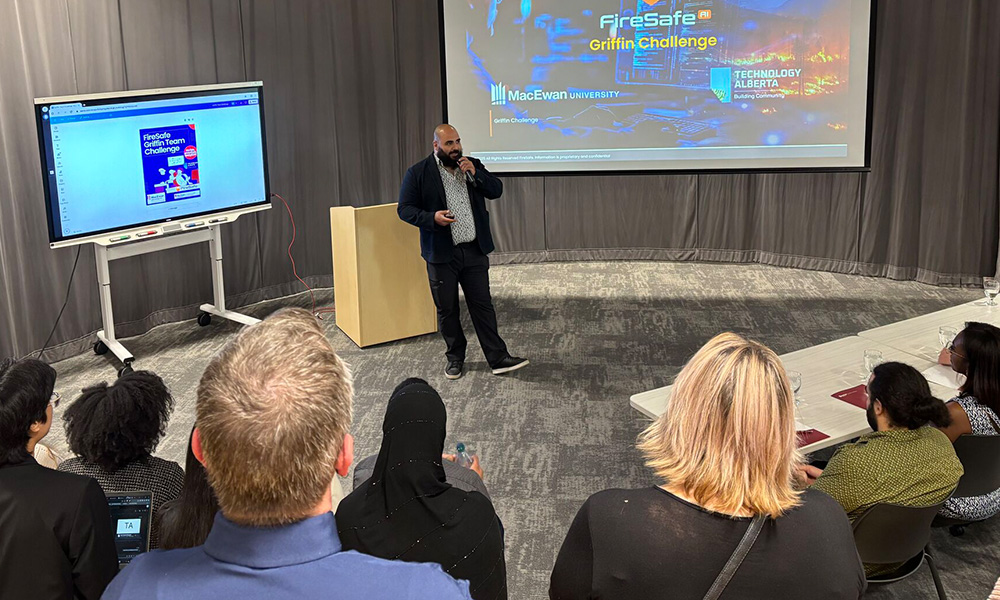A man presents in front of an audience with a screen in the background